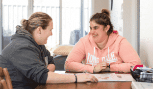 Kurrajong staff member chatting to Kurrajong client while sitting at a table in a supported living house