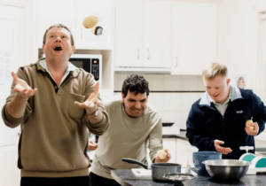 Housemates Jason, Tim, and Luke have fun in the kitchen of their home.