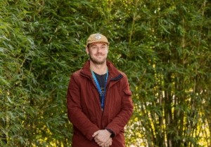 Group facilitator Jake Ploenges, in front of green trees